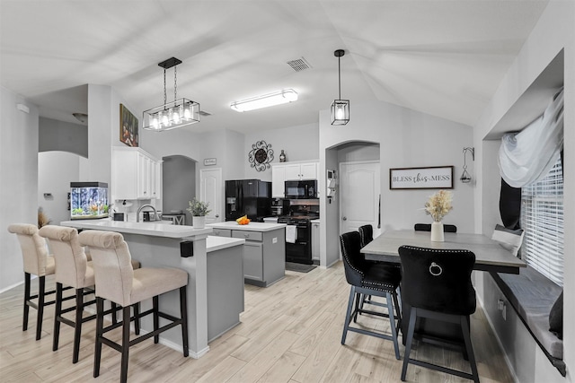 kitchen with light wood-type flooring, black appliances, hanging light fixtures, gray cabinetry, and white cabinets