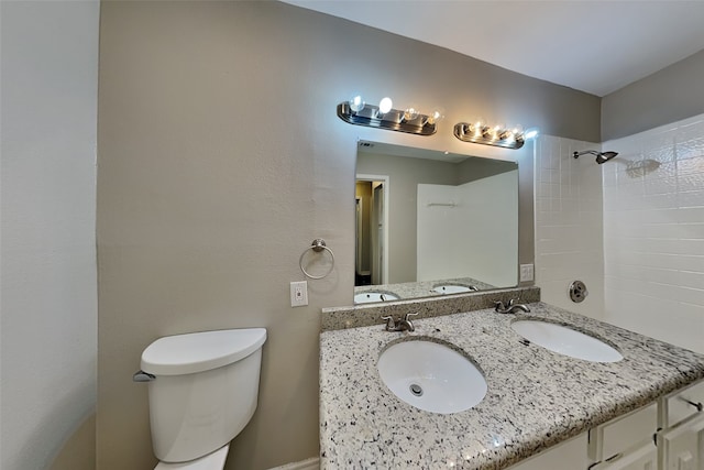 bathroom featuring vanity, toilet, and a tile shower