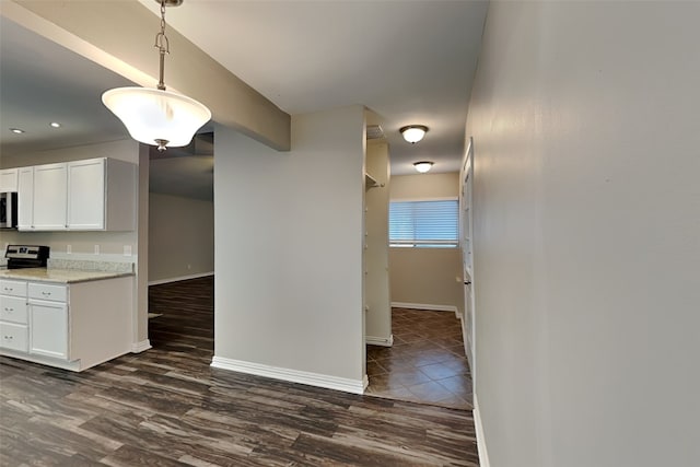 kitchen with dark wood-type flooring, white cabinets, hanging light fixtures, and light stone counters