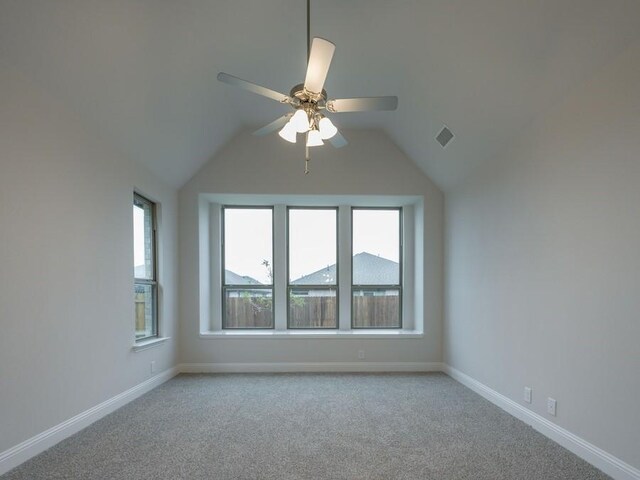 spare room featuring ceiling fan, light carpet, and vaulted ceiling