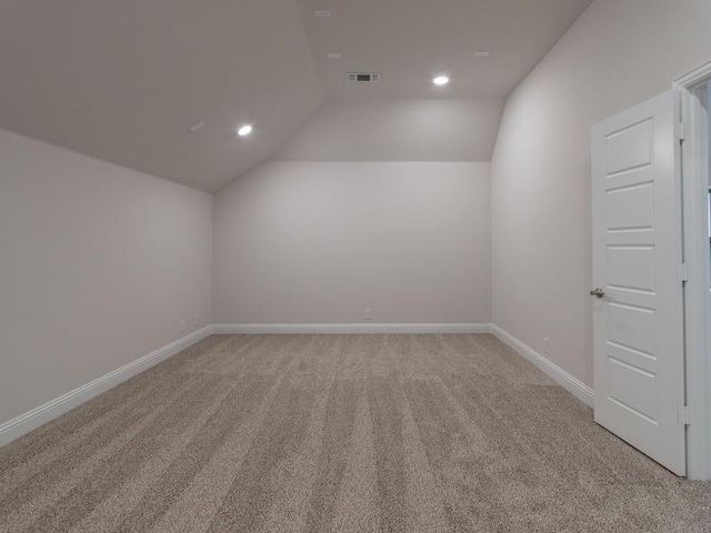 carpeted empty room featuring vaulted ceiling