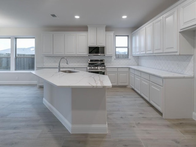 kitchen with white cabinetry, sink, light stone countertops, decorative backsplash, and appliances with stainless steel finishes