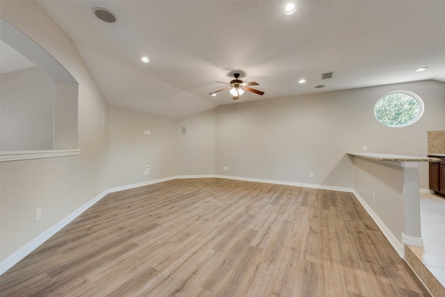 empty room with light wood-type flooring, vaulted ceiling, and ceiling fan