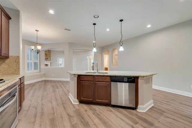 kitchen featuring light wood-type flooring, stainless steel appliances, an inviting chandelier, an island with sink, and sink