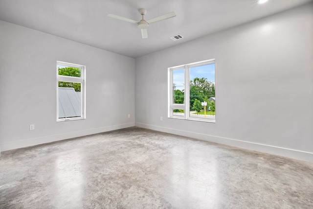 empty room with a wealth of natural light, concrete floors, and ceiling fan