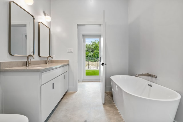 bathroom featuring a tub to relax in, concrete floors, and vanity