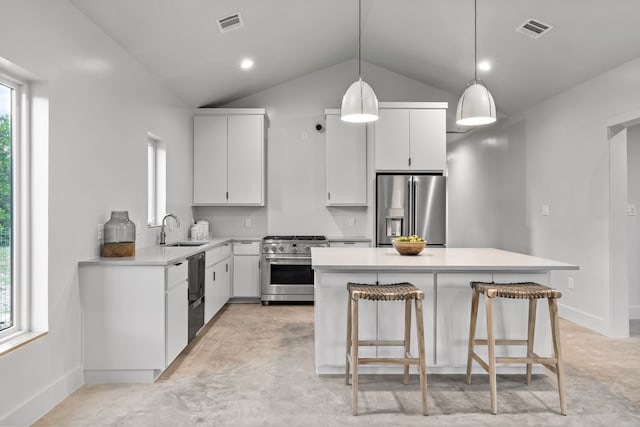 kitchen with vaulted ceiling, hanging light fixtures, stainless steel appliances, sink, and white cabinetry