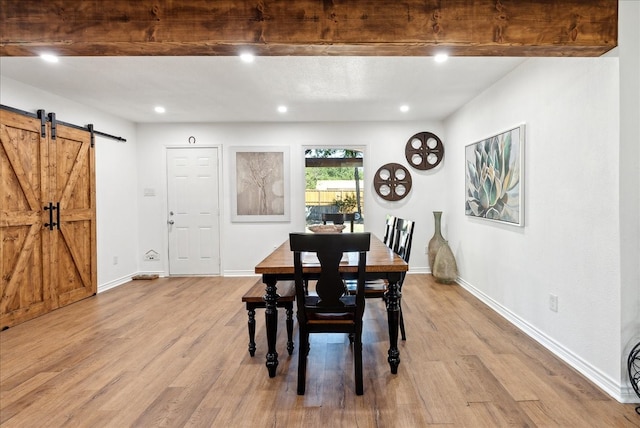 dining area featuring a barn door and light hardwood / wood-style floors