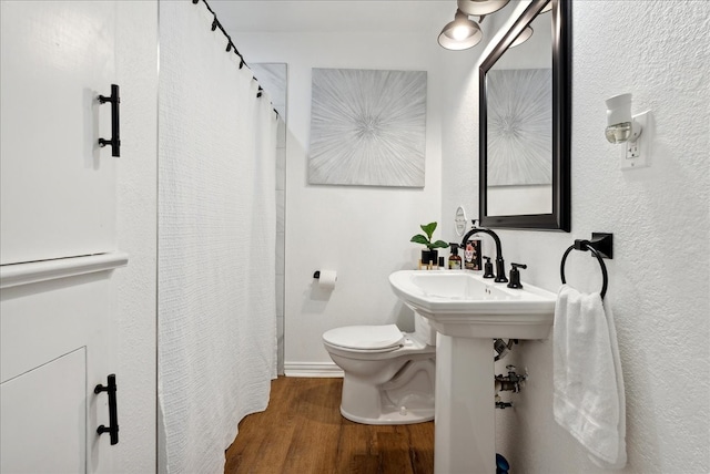 bathroom featuring toilet, hardwood / wood-style flooring, and curtained shower