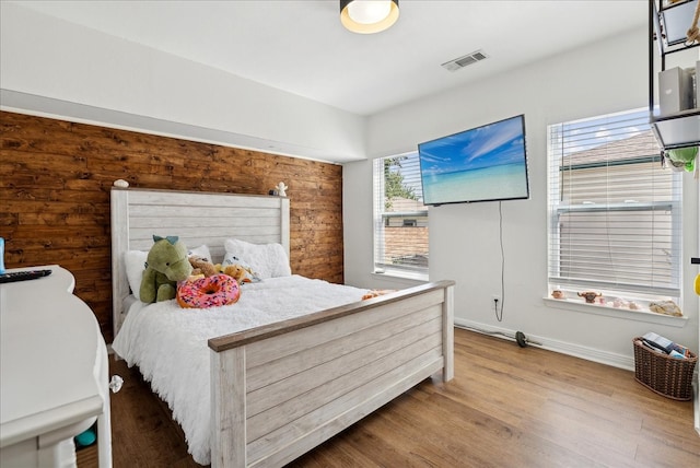 bedroom featuring light wood-type flooring and wooden walls