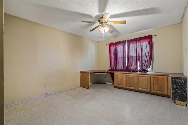 unfurnished office with ceiling fan and a textured ceiling