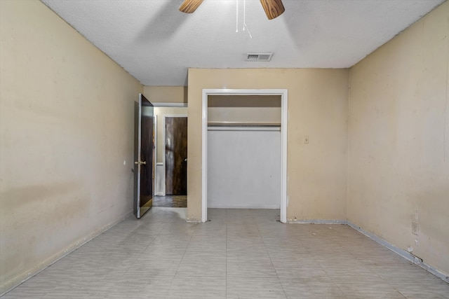 unfurnished bedroom with a textured ceiling, ceiling fan, and a closet