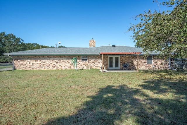 back of property with french doors, a patio area, and a yard