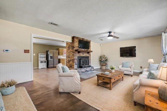 living room with hardwood / wood-style flooring, a brick fireplace, and ceiling fan