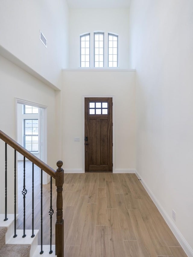 entryway with a towering ceiling and light hardwood / wood-style floors