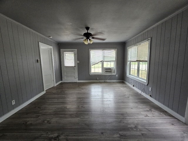 interior space with dark hardwood / wood-style floors, ceiling fan, ornamental molding, and wooden walls