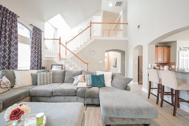 living room with light wood-type flooring and high vaulted ceiling