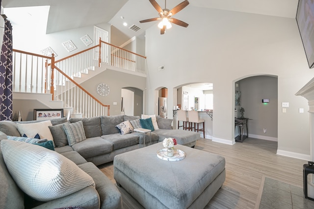 living room with high vaulted ceiling, ceiling fan, and light hardwood / wood-style floors