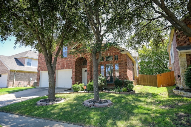 traditional-style home with brick siding, fence, a front yard, a garage, and driveway