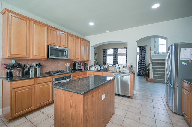 kitchen with plenty of natural light, a center island, stainless steel appliances, and dark stone counters