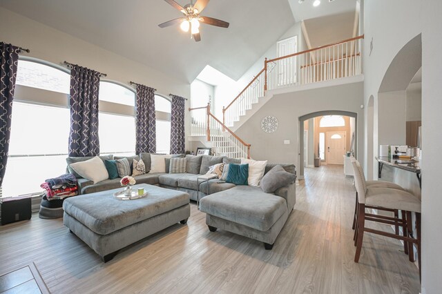 living room with a wealth of natural light, high vaulted ceiling, and light wood-type flooring