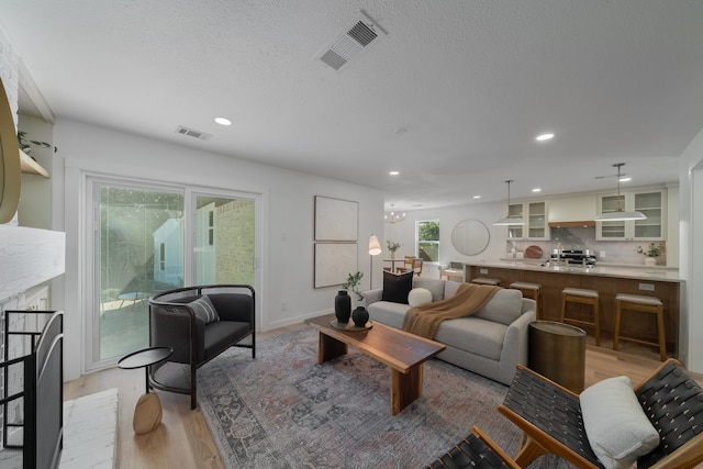 living room featuring a brick fireplace, a textured ceiling, and light hardwood / wood-style flooring