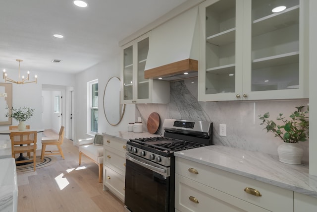 kitchen with gas range, an inviting chandelier, light hardwood / wood-style flooring, backsplash, and white cabinets