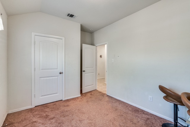 unfurnished bedroom with light carpet and lofted ceiling