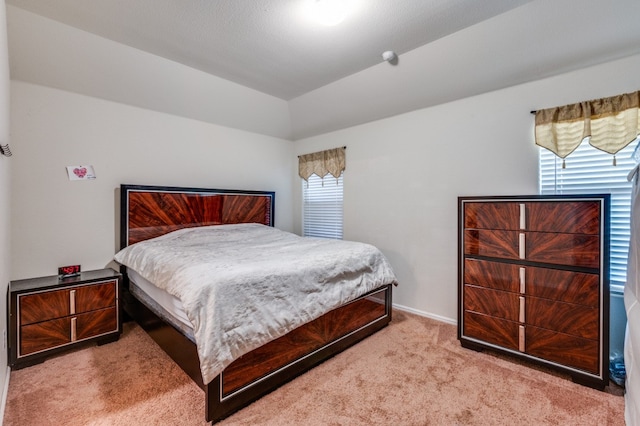 bedroom with light carpet and lofted ceiling