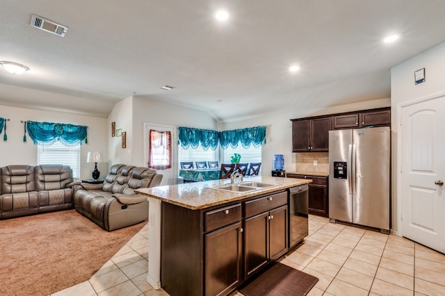 kitchen featuring appliances with stainless steel finishes, dark brown cabinetry, vaulted ceiling, sink, and an island with sink