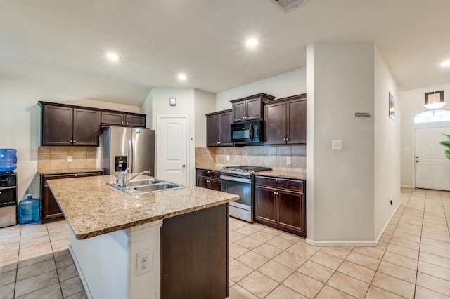 kitchen with a center island with sink, sink, light tile patterned floors, tasteful backsplash, and stainless steel appliances