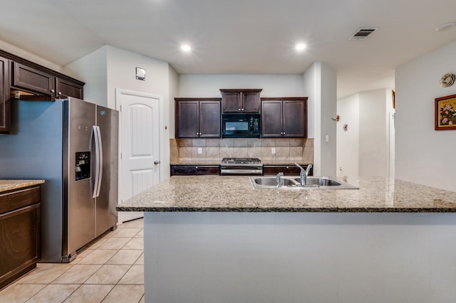 kitchen featuring appliances with stainless steel finishes, dark brown cabinetry, a kitchen island with sink, and sink