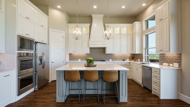 kitchen featuring white cabinets, a center island, an inviting chandelier, appliances with stainless steel finishes, and dark hardwood / wood-style flooring