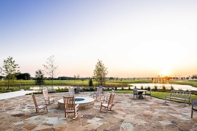 patio terrace at dusk with an outdoor fire pit and a water view