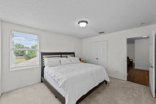 carpeted bedroom with a textured ceiling and a closet