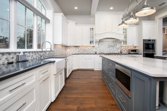 kitchen featuring pendant lighting, dark hardwood / wood-style floors, white cabinetry, gray cabinetry, and appliances with stainless steel finishes