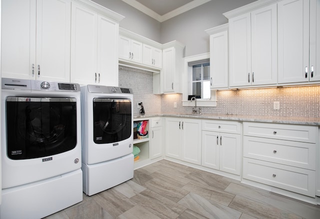 clothes washing area featuring ornamental molding, cabinets, separate washer and dryer, and sink