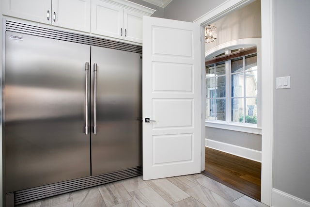 kitchen with white cabinets, a chandelier, built in fridge, light wood-type flooring, and crown molding