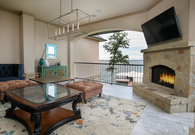 living room featuring crown molding and a stone fireplace