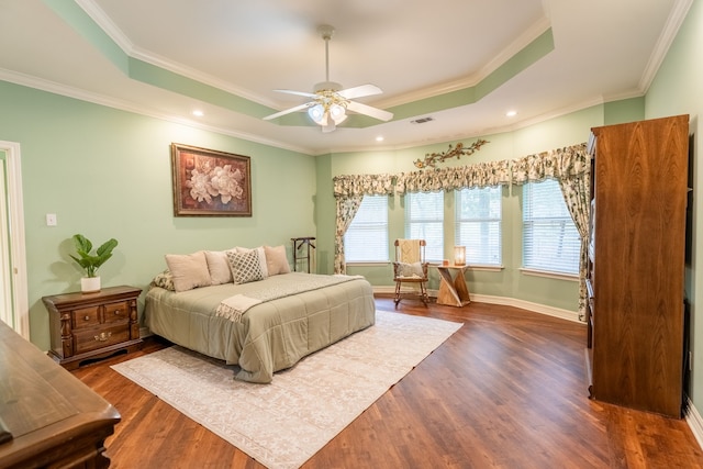 bedroom with ceiling fan, dark hardwood / wood-style flooring, ornamental molding, and a tray ceiling