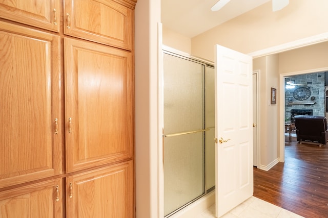 bathroom with a fireplace, wood-type flooring, and a shower with shower door