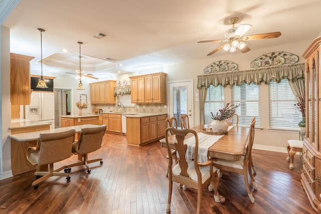 dining room with ceiling fan, dark hardwood / wood-style flooring, crown molding, and a tray ceiling