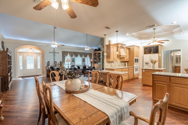 dining room with a raised ceiling, ceiling fan, ornamental molding, and hardwood / wood-style flooring