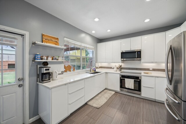 kitchen featuring white cabinets, sink, stainless steel appliances, and a wealth of natural light