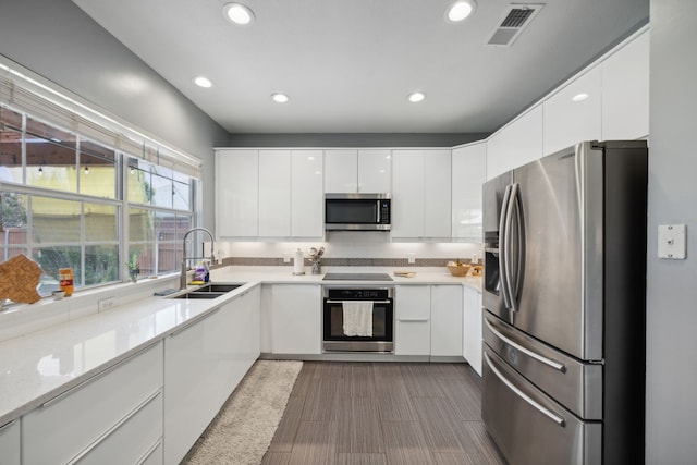 kitchen featuring tasteful backsplash, sink, white cabinets, appliances with stainless steel finishes, and light stone countertops