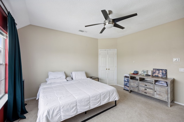 bedroom with light carpet, a closet, lofted ceiling, and ceiling fan