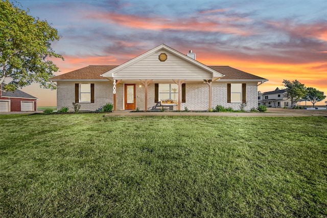 view of front of home with a yard, covered porch, and a garage