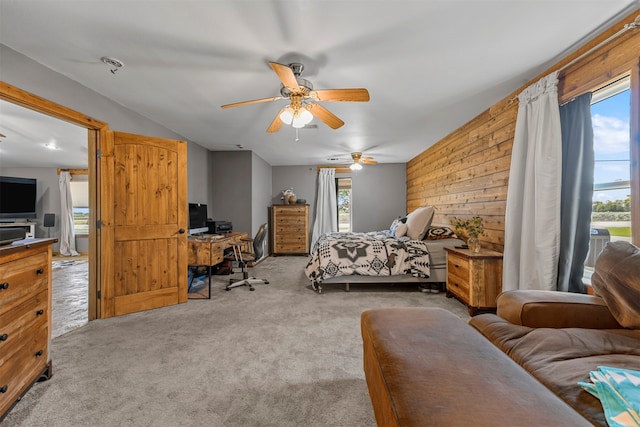 carpeted bedroom with multiple windows, wood walls, and ceiling fan