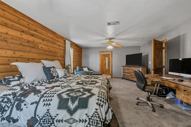 carpeted bedroom featuring ceiling fan and wood walls