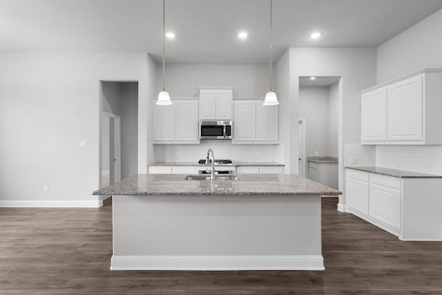 kitchen with sink, white cabinetry, pendant lighting, and light stone countertops